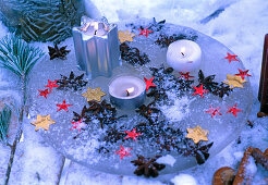Candle tray made of ice with aniseed fruits and stars in it