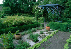 Small herb garden and salad beds next to box hedges in front of small pavilion