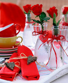 Rosa (rote Rosen) in Glasflaschen mit Herzen aus Pappe