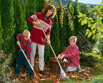 Woman with two boys raking leaves