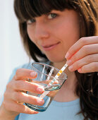 Frau taucht pH-Teststreifen in Wasser