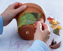Clay pot wrapped in autumn leaves
