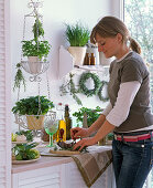 Kitchen with herbs on wall shelf, in a hanging basket and on a sideboard