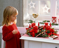 Girl lights candles on Advent wreath with Juniperus, Abies