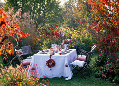 Table in front of autumn bed with miscanthus (Chinese reed) in the evening