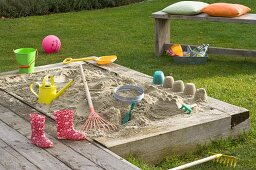Sandbox with toys and kids rubber boots
