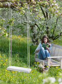 Swing suspended from branch of flowering Malus (apple tree)