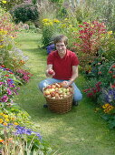 Young man with freshly harvested apples in wicker basket