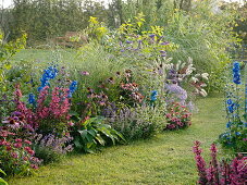 Lawn path between beds with perennials, summer flowers and grasses
