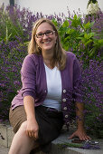 Garden owner sitting on the wall next to lavender (Lavandula)