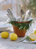 Wreath of herbs around clay pot with cutlery