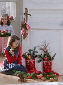 Mädchen neben roten Nikolausstiefeln, gefüllt mit Abies (Tanne), Äpfeln