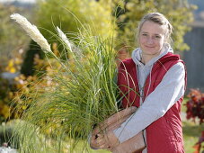 Frau hält Cortaderia selloana 'Pumila' (Mini-Pampasgras) im Arm