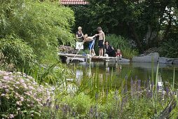 Swimming pond with wooden walkway bordered with granite blocks