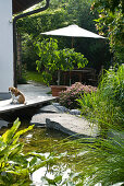 View from swimming pond to wooden seating area under parasol