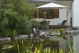 View from the pond to the terrace with wicker furniture