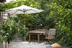 Kleine gepflasterte Terrasse mit hölzernen Möbeln und Sonnenschirm
