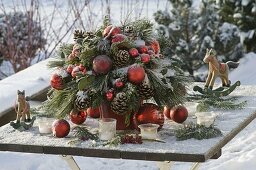 Gefrorener Weihnachtsstrauß aus Pinus (Kiefer) Zweige und Zapfen , Ilex