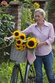 Frau mit Fahrrad und Sonnenblumen