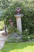Artist's garden: Garden art in front of a corkscrew hazel tree