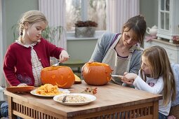 Mother with daughters makes pumpkin heads