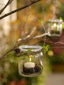 Canning jar as lantern with wire hanger hung on tree
