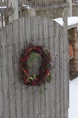 Garden gate with wreath of Cornus (dogwood), Ilex (holly) and Pinus