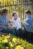 Frau und Kinder mit Osternest im Bauerngarten