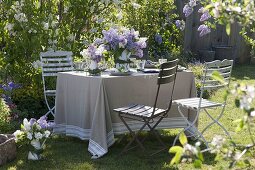 Lilac table decoration in the garden in front of lilac bushes