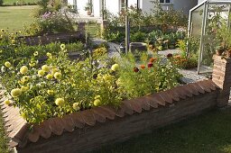 Kleiner Bauerngarten mit Mauer, Brunnen in der Mitte, gepflasterte Wege