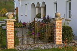 Garden gate with brick posts, paved path, bed with aster