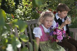 Mädchen im Dirndl mit Duftstrauß aus Rosa (Rosen) und Lathyrus odoratus