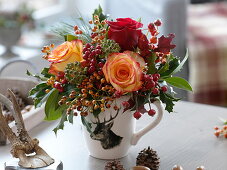 Hirsch-Tasse als Vase mit Rosa (Rosen, Hagebutten), Hedera (Efeu)