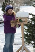 Girl filling bird house with sunflower seeds