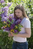 Woman with fragrant bouquet of Syringa (lilac) and Ranunculus acris