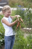 Girl with freshly harvested carrots (Daucus carota)