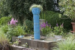 Getöpferte blaue Säule mit Kopf als Wasserspeier