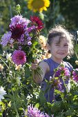 Mädchen pflückt Blumen für Spaetsommerstrauss