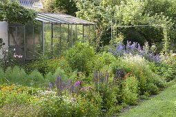 Colourful bed with summer flowers, perennials, vegetables and herbs