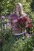 Junge Frau schneidet die letzten Sommerblumen im Bauerngarten