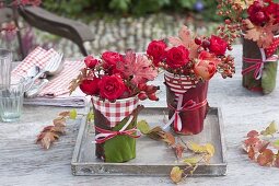 Red and white drinking cups as vases with Bergenia leaves