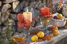 Herbstliche Kerzendeko mit Blättern, Rosa (Hagebutten) und Chaenomeles