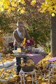 Family at the table in golden autumn leaves under maple tree