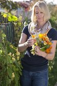 Woman picking bouquet of summer flowers with edible blossoms