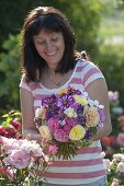 Frau mit Gartenstrauss aus Rosa (Rosen), Hydrangea (Hortensien), Cosmos