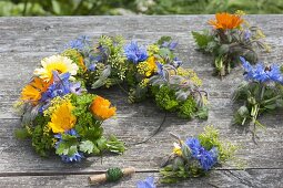 Blau-gelb-oranger Kranz aus essbaren Blüten und Kräutern