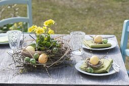 Ostertischdeko mit Kranz aus Zweigen, Gräsern und gelber Primel