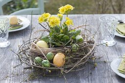 Ostertischdeko mit Kranz aus Zweigen, Gräsern und gelber Primel