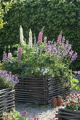 Gravel terrassse with raised beds made of hazelnut rods