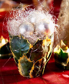 Clay pot with holly leaves and Christmas decoration with angel hair